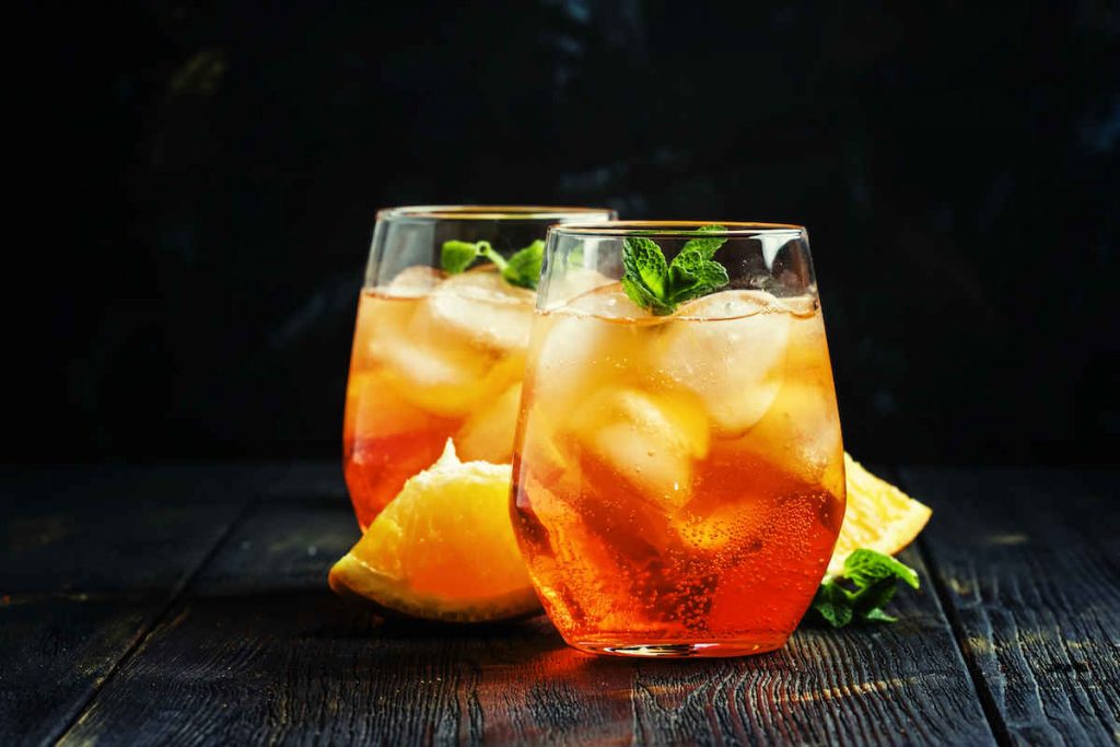 two Aperol Spritz with lemon wedges and mint garnish