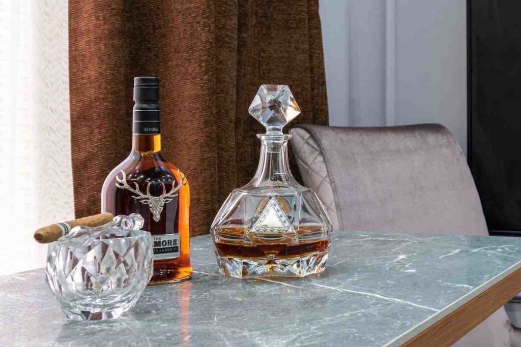 scotch bottle and decanter with a cigar and crystal ashtray