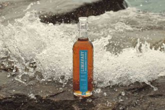 Limavady Single Malt Irish Whiskey bottle on the beach with crashing waves