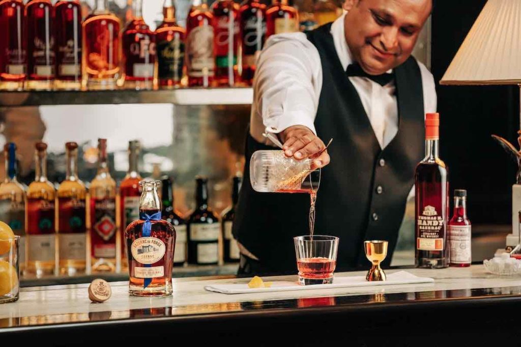 bartender pours a cocktail made with Sazerac de Forge Cognac