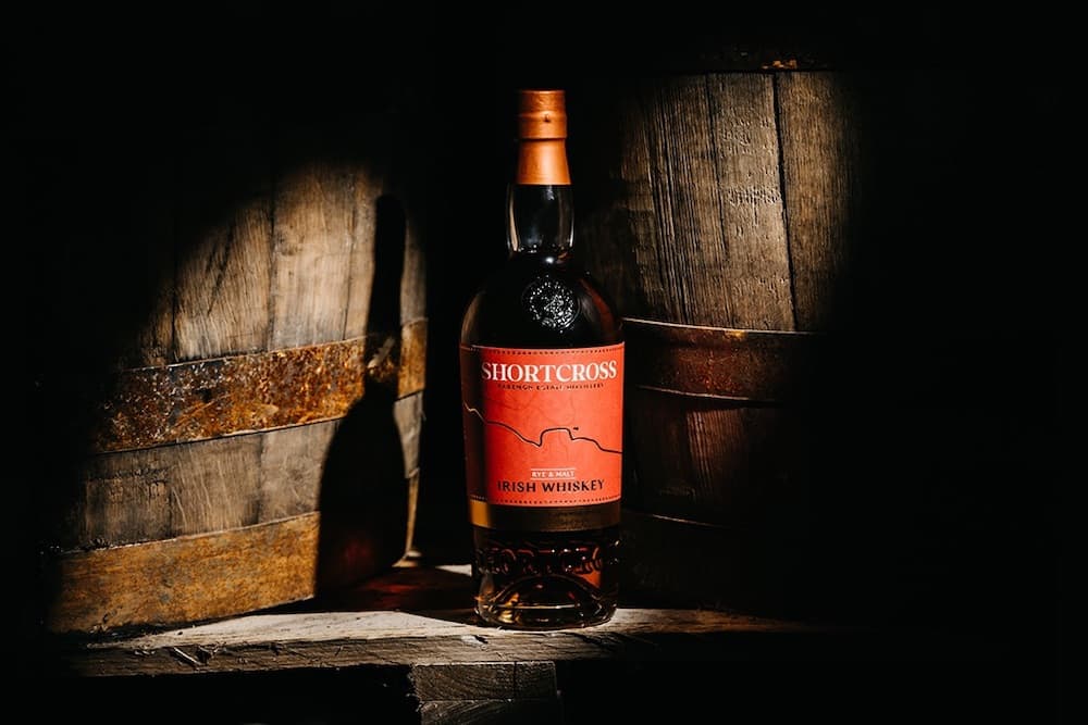 a bottle of Shortcross Rye & Malt Irish Whiskey sitting on barrels