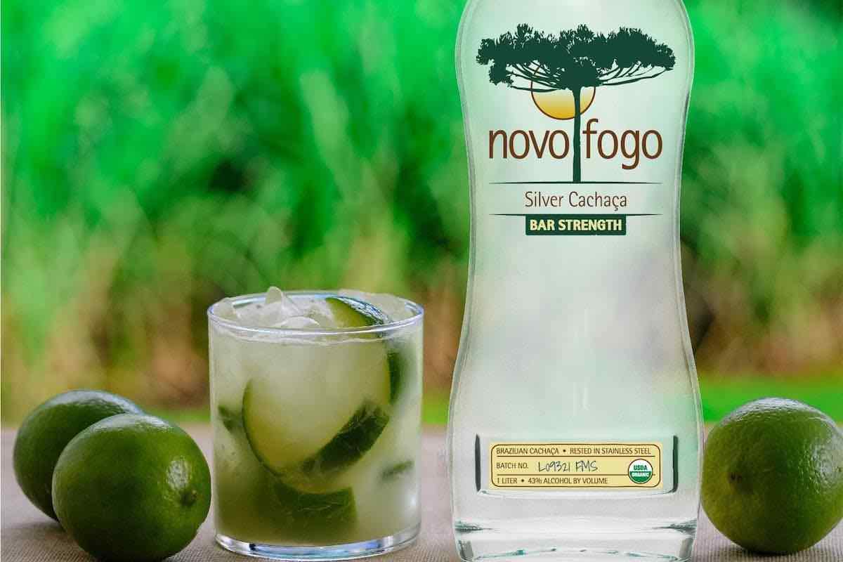 bottle of Novo Fogo Bar Strength Cachaça with caipirinha and limes